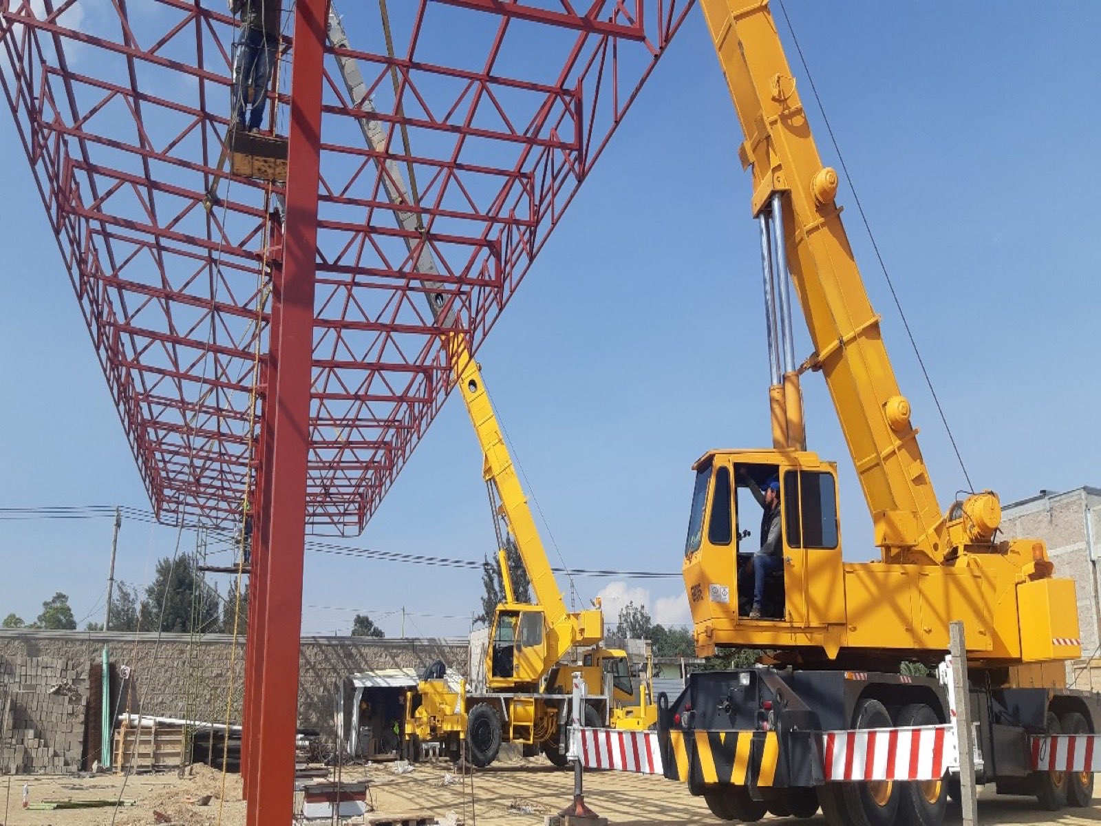 Grúa telescópica montando estructura de acero en obra industrial