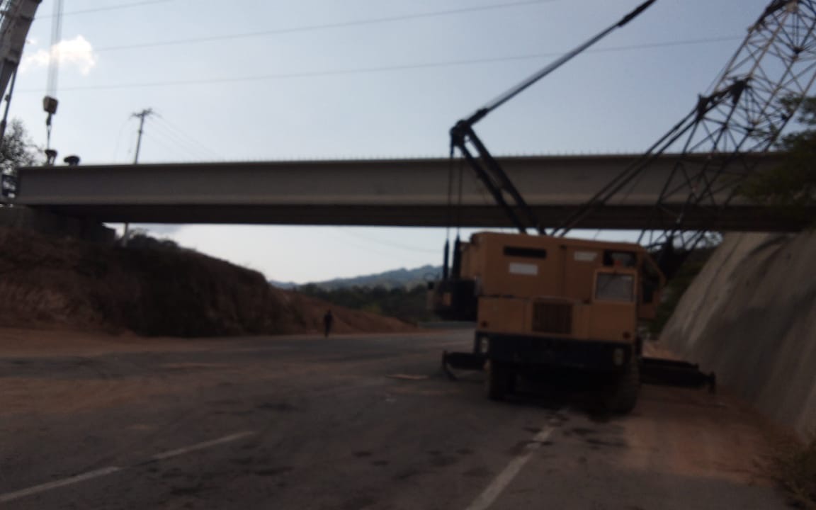 Grúa de Grúas Trejo colocando una trabe de puente sobre corte de camino en terreno rural
